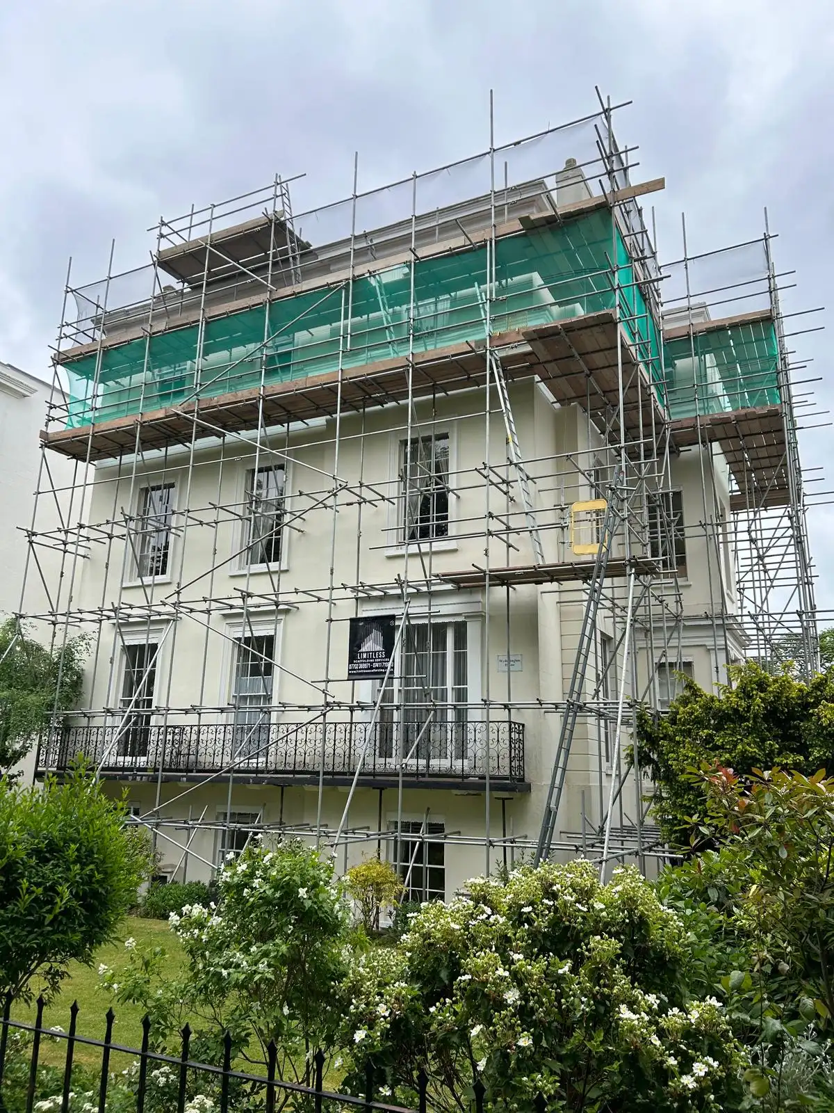Scaffolding and green sheeting around a large residential property
